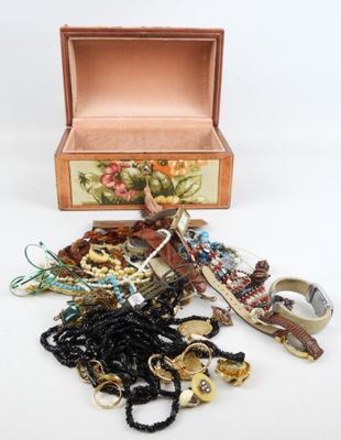 une boîte en bois remplie de bijoux variés, posée sur une surface blanche