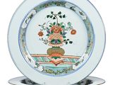 une assiette sur laquelle est disposée une composition florale, posée sur un support à assiette