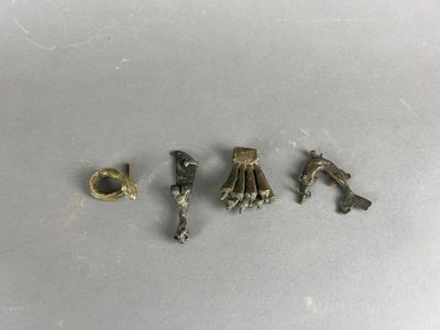 quatre pièces métalliques sont disposées en ligne sur une surface blanche