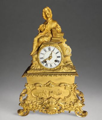 a gold clock with a statue on top of it