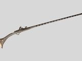 un vieux pistolet avec une crosse en bois sur fond gris