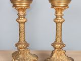 pair of antique brass candlesticks on wooden table against blue wall