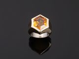 a ring with a faceted citrine stone on a black surface