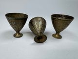 Trois vases en laiton ancien sont posés sur une surface blanche