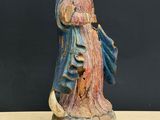 an old statue of a woman holding a cat on a table