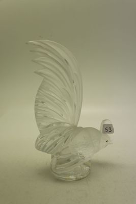 une figurine en verre représentant un oiseau posée sur une surface blanche