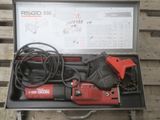 un outil rouge et noir dans un étui posé sur une table en bois
