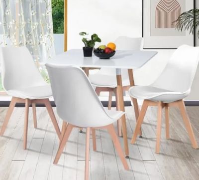 a white table with four chairs and a bowl of fruit on it