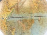 une personne tenant un appareil photo à côté d'un grand globe terrestre