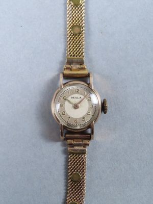 un gros plan d'une montre-bracelet posée sur une surface bleue