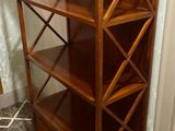 une bibliothèque en bois à quatre étagères, sur laquelle est posé un vase