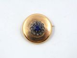 a close up of a gold button with a blue stone in the center