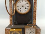 une horloge posée sur une table, à côté de deux petites horloges