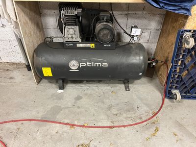 un petit compresseur d'air dans un garage, avec un tuyau rouge