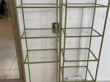 two gold metal shelvings with glass shelves on them