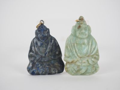 deux pendentifs représentant des bouddhas en jade, l'un vert et l'autre bleu, sur fond blanc