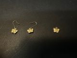 a pair of gold earrings with a butterfly on them on a black surface