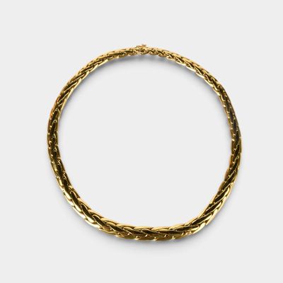 gros plan d'un bracelet en or sur fond blanc