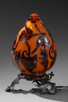 un vase orange et noir posé sur un socle en métal