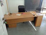 un bureau en bois sur lequel se trouve un ordinateur, dans une pièce