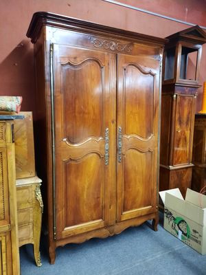 une grande armoire en bois dans une pièce où se trouvent de nombreux autres meubles