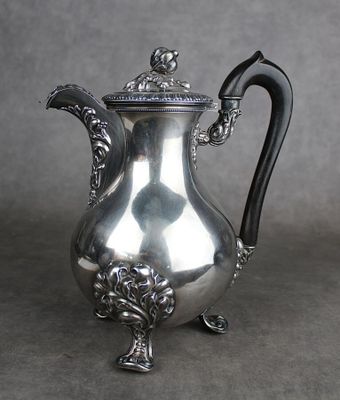 une cafetière ancienne en argent avec une poignée noire sur fond gris
