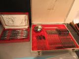 des couverts rangés dans un coffret rouge, posés sur une table à côté d'autres couverts