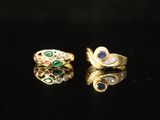 a pair of gold rings with emeralds and sapphires on a black surface