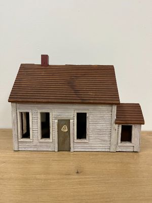 a small white house with a brown roof on a wooden table