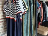 clothes hanging on a rack in a clothing store next to a brick wall