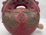 a red vase with a dragon on it on a white surface