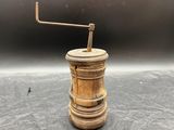 un vieux moulin à poivre en bois posé sur une table