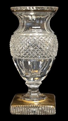 un vase en verre avec un socle doré sur fond noir