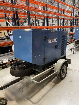 une remorque transportant une machine bleue, dans un entrepôt