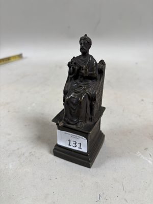 une petite statue représentant une femme assise sur une chaise