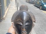 a person holding a mask on the sidewalk in front of a building