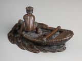 a statue of a man sitting in a boat with a paddle