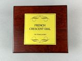 french crescent dial on a wooden box on a white surface