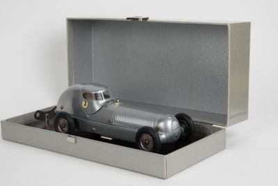 une petite voiture argentée dans une boîte argentée posée sur une surface blanche