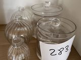 trois récipients en verre transparent posés sur une table, accompagnés d'une étiquette de prix