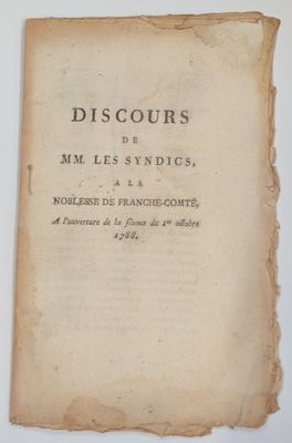 un vieux livre posé sur une table à côté d'une tasse de café