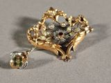 a gold brooch with green and white stones on it