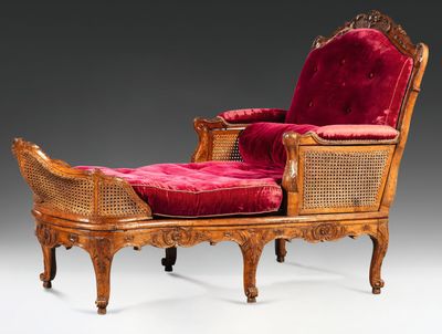 an antique wooden chair with red velvet upholstered seat and foot rest