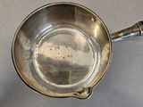 a small silver pan with a handle on a table