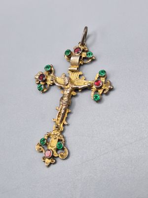 un gros plan d'une croix en or sertie de pierres vertes et roses