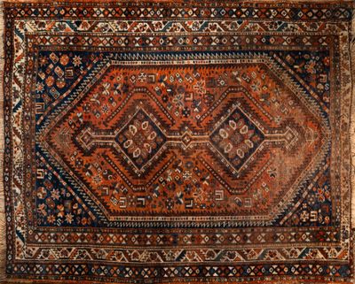 un vieux tapis persan aux motifs géométriques posé sur un parquet