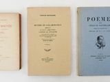three books are lined up on a white surface, one of them is open