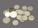 some silver coins on a gray surface with a coin in the foreground