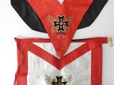 un gros plan sur un tablier rouge et blanc orné d'une croix