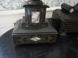 une petite horloge posée sur une table, à côté d'une boîte noire